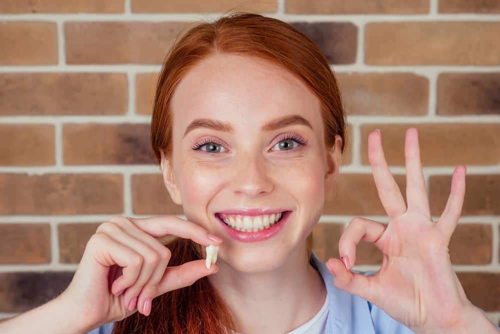 Female Smiling Holding Wisdom Tooth