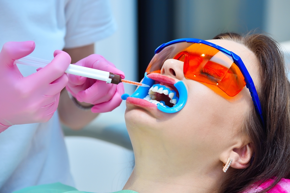 Dentist applies whitening gel to woman's teeth