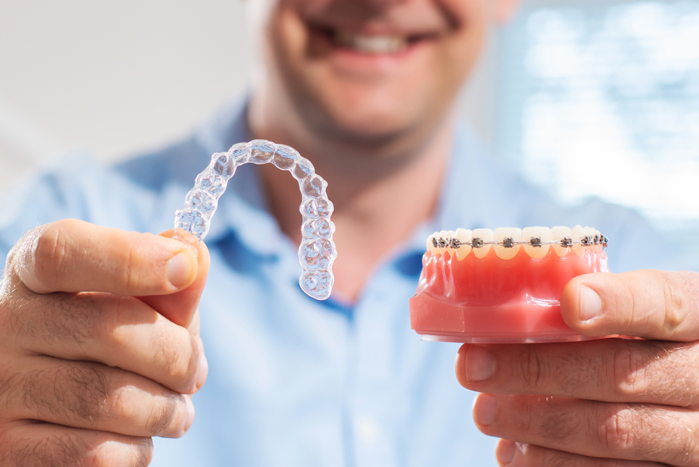 doctor holding aligners and braces in hand